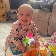 Emmie joined the competition — help win amazing prizes! baby, child, indoor, toy, play, smile, onesie, disney, table, colorful, happy, carpet, furniture, living_room, pacifier, window, curtains, couch, radiator, home