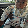 Iyon joined the competition — help win amazing prizes! baby, child, infant, cartoon_clothing, car_interior, hand, blue_nail_polish, window, trees, light_pole, curious_look, cozy_outfit, bib, long_sleeves, pants, sitting, portrait, dark_skin, indoor, daylight