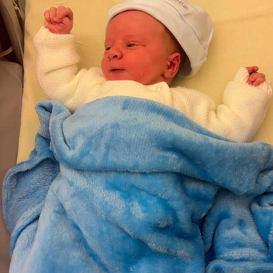 Lorenzo a rejoint le concours — aidez-le/la à gagner de superbes lots ! baby, bed, blanket, blue_blanket, child, cushion, cute, face, indoors, infant, lying_down, newborn, peaceful, resting, sleepwear, small_hands, soft_texture, warm, white_hat, white_sweater