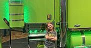 Chevy is registered to the contest to win money with this photo: arms_crossed, casual, child, clothing, floor, green, hair, indoor, lights, metal, person, reflection, semi_truck, shoes, shorts, smile, standing, truck, tshirt, vehicle