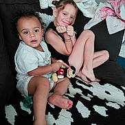 Cheyanne is registered to the contest to win money with this photo: child, children, couch, plush_toy, mickey_mouse, blanket, carpet, foot, smile, happy, indoor, casual_clothing, hair, face, sitting, toy, cute, relaxed, home, siblings