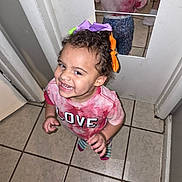 Cheyanne joined the competition — help win amazing prizes! toddler, child, smile, happy, indoor, tile_floor, door, mirror, reflection, colorful_bows, hair_accessories, pink_shirt, tie_dye, love_text, socks, curly_hair, person, cute, playful, young_child
