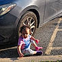 Cheyanne joined the competition — help win amazing prizes! child, toddler, car, parking_lot, toy, socks, grass, sidewalk, curly_hair, sunlight, asphalt, road_marking, clothing, playing, outdoor, person, vehicle, wheel, casual, daytime