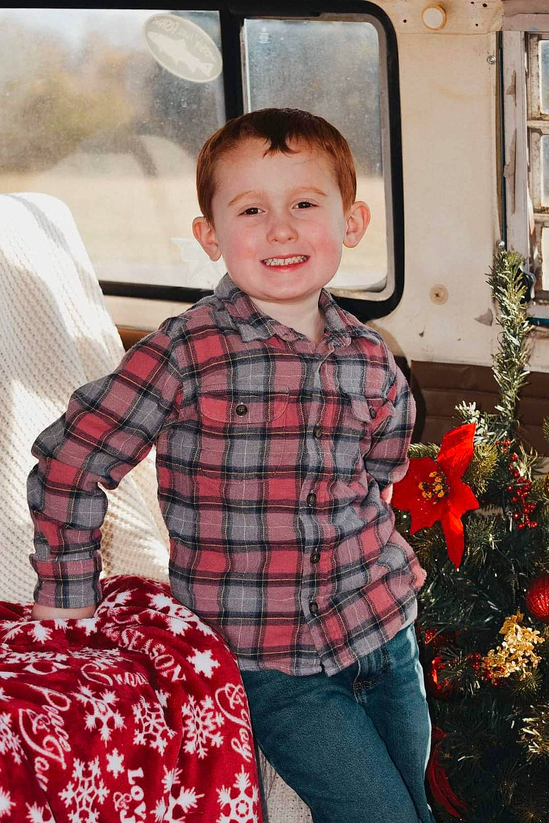 Zane is registered to the contest to win money with this photo: child, christmas_decoration, christmas_ornament, event, face, hair, happy, head, holiday, joy, pattern, person, plaid, plant, red, sleeve, smile, tartan, toddler, tree
