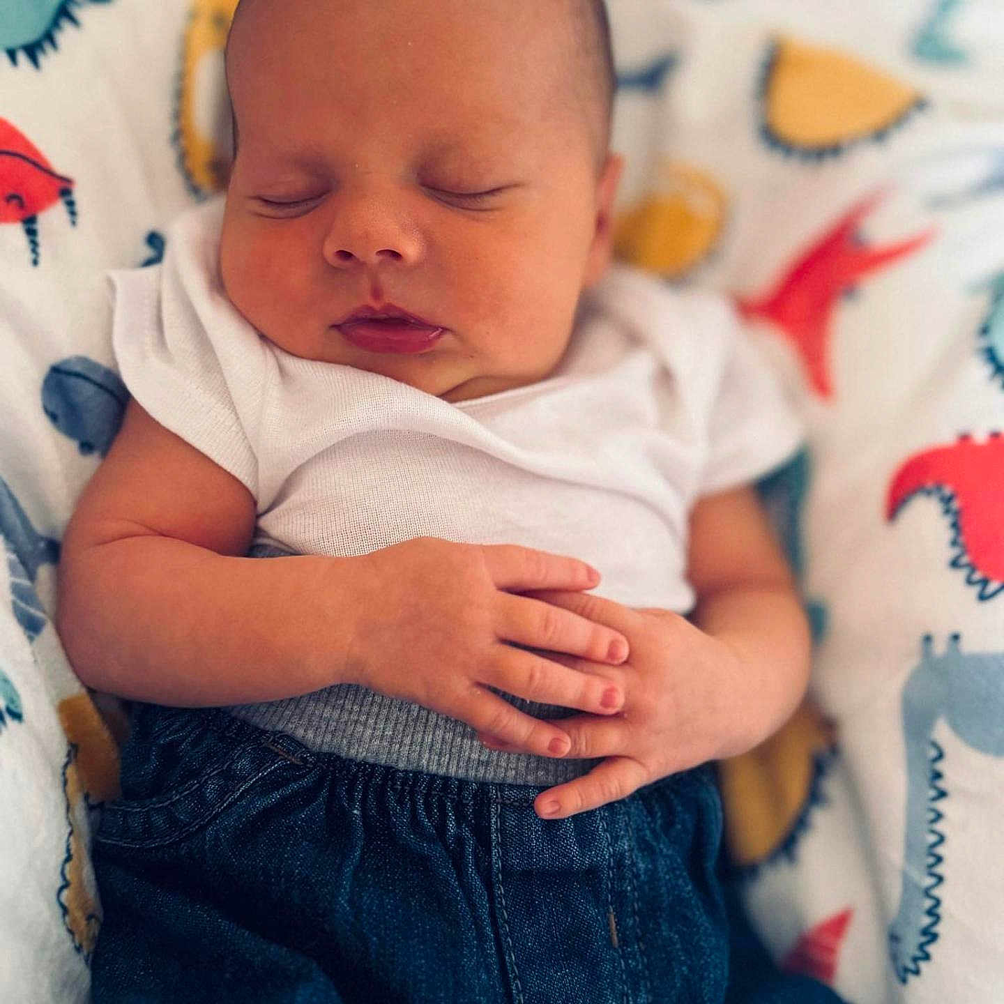 Caspiayn is registered to the contest to win money with this photo: baby, blanket, calm, child, closeup, cute, denim_pants, dinosaur_pattern, hands, indoor, infant, newborn, onesie, peaceful, portrait, relaxed, resting, skin, sleeping, soft_light