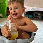 Meyson participe au concours pour gagner de l'argent avec cette photo : child, boy, smiling, indoor, plastic_tub, bottle, drink, happy, cute, blue_eyes, hair, skin, sitting, playful, joyful, floor, background_blur, person, toddler, fun