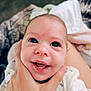 baby, smiling, hand, face, infant, person, clothing, closeup, skin, eyes, mouth, expression, cute, human, newborn, blanket, comfort, holding, portrait, happy