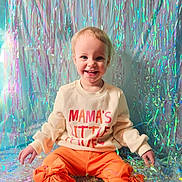 Arwyn is registered to the contest to win money with this photo: toddler, child, smiling, sweater, orange_pants, bows, holographic_background, sitting, happy, portrait, indoor, colorful, cute, fashion, young_child, playful, clothing, face, person, bright