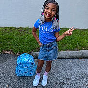 K Couture is registered to the contest to win money with this photo: child, girl, smiling, peace_sign, blue_shirt, denim_skirt, braided_hair, beaded_hair, backpack, outdoor, sidewalk, grass, wall, casual_clothing, white_shoes, pink_socks, happy, standing, portrait, youth