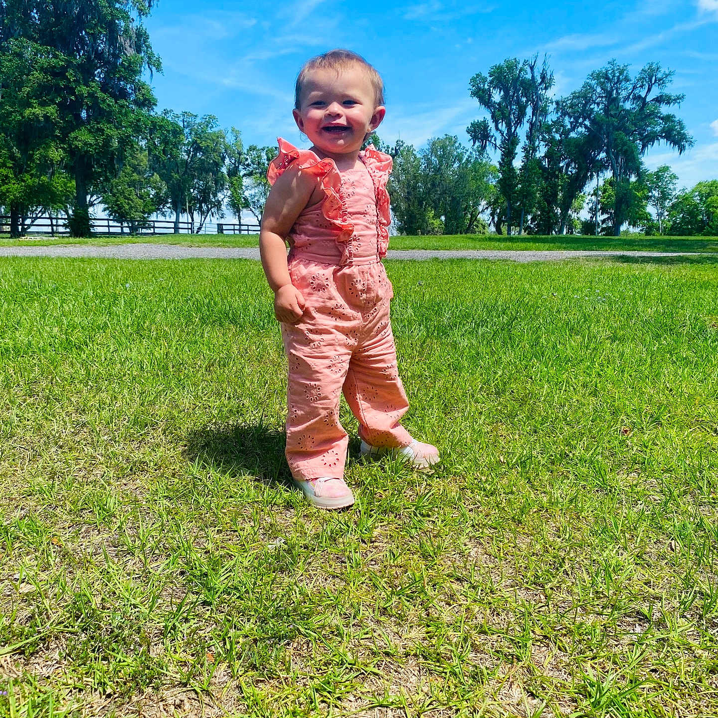 Kamilla joined the competition — help win amazing prizes! blue_sky, casual_clothing, child, daytime, footwear, grass, greenery, happy, nature, outdoor, person, pink_outfit, playful, portrait, smiling, standing, sunny, toddler, trees, young_child