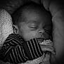 baby, newborn, sleeping, infant, close_up, black_and_white, blanket, swaddle, striped_clothing, peaceful, portrait, soft_lighting, hand, cheek, nose, eyelashes, cozy, bed, knit, monochrome