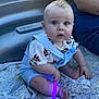 Cayden joined the competition — help win amazing prizes! baby, child, infant, sitting, blue_overalls, superhero_tshirt, pacifier, glowing_stick, purple_light, quilt, blanket, indoor, person, cute, curly_hair, wide_eyes, hand, foot, adult_arm, casual_clothing