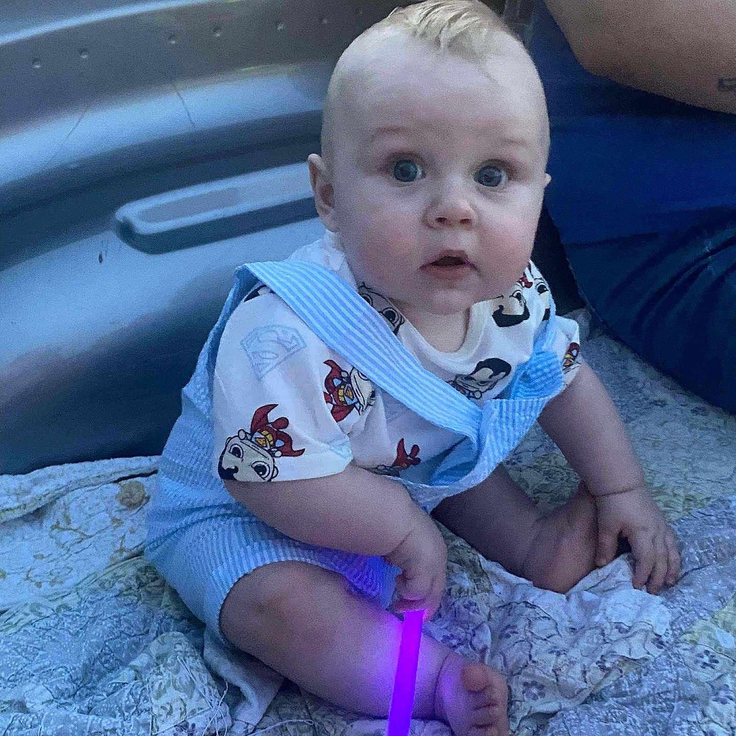 Cayden joined the competition — help win amazing prizes! adult_arm, baby, blanket, blue_overalls, casual_clothing, child, curly_hair, cute, foot, glowing_stick, hand, indoor, infant, pacifier, person, purple_light, quilt, sitting, superhero_tshirt, wide_eyes