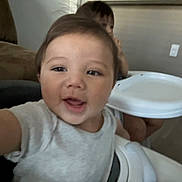 Jairo joined the competition — help win amazing prizes! child, toddler, high_chair, indoor, happy, smiling, person, face, baby, furniture, table, seat, clothing, arm, head, background, room, wall, floor, playful