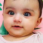 Aarna joined the competition — help win amazing prizes! baby, cheeks, child, closeup, colorful_background, curious, cute, face, flower_pattern, hair_clip, head, indoor, infant, large_eyes, person, pink_clothing, portrait, skin, smile, young_child