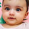 baby, child, face, portrait, infant, cute, smile, hair_clip, pink_clothing, large_eyes, closeup, indoor, colorful_background, flower_pattern, young_child, skin, head, cheeks, curious, person