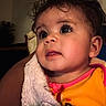 Riley joined the competition — help win amazing prizes! baby, infant, child, face, eyes, curly_hair, blanket, cozy, indoors, portrait, cute, expression, clothing, orange_outfit, pink_trim, warm_lighting, skin, head, person, closeup