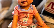 Riley joined the competition — help win amazing prizes! baby, child, infant, pink_bow, dinosaur_outfit, cute, smiling, sitting, indoors, person, hand, foot, legs, clothing, headwear, happy, portrait, home, couch, family