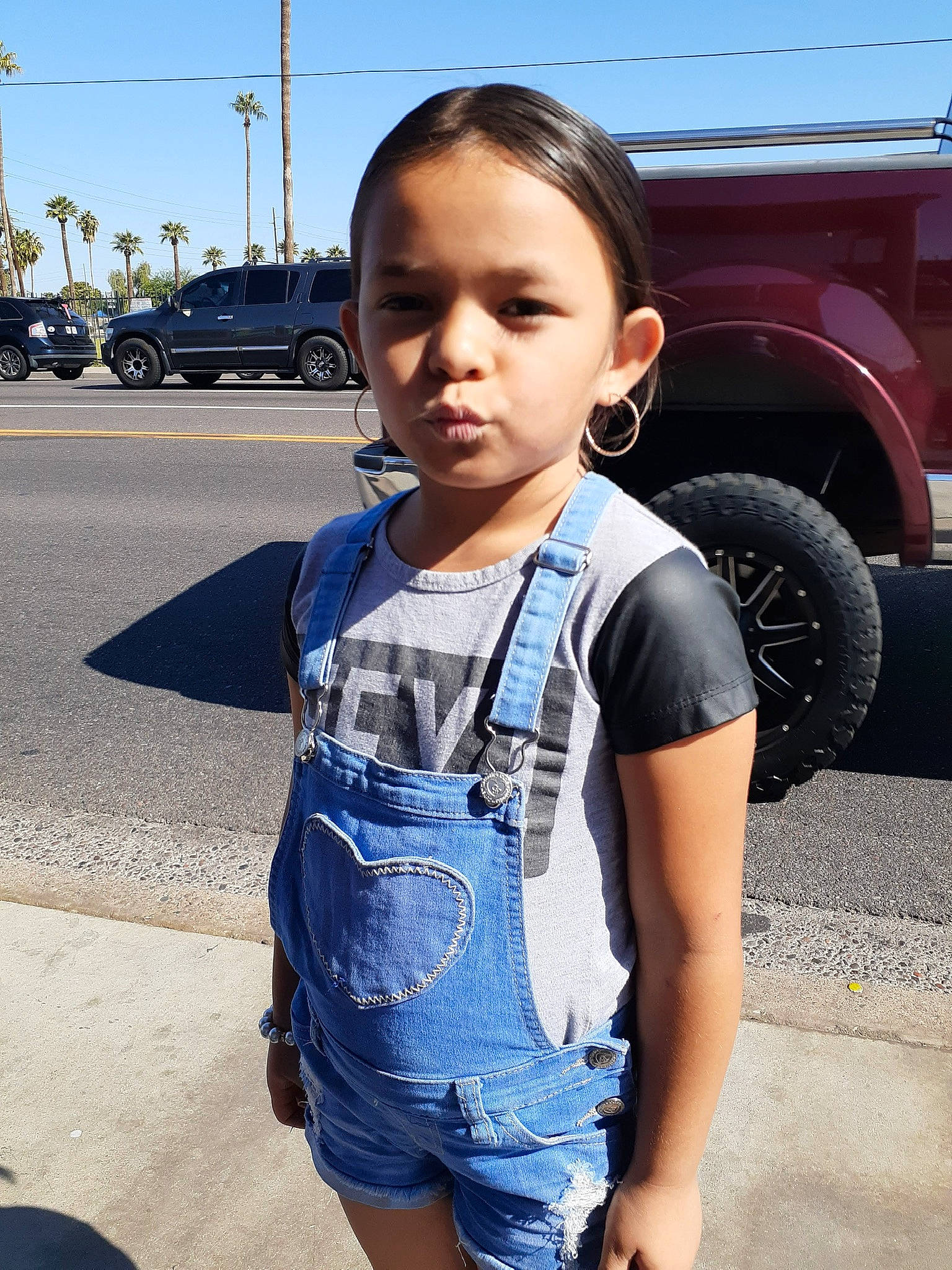 Aaliyah is registered to the contest to win money with this photo: asphalt, automotive_tire, cool, daytime, facial_expression, hairstyle, happy, head, motor_vehicle, person, product, public_space, shoulder, sky, sleeve, standing, street_fashion, tire, travel, vehicle