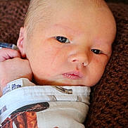 Weston is registered to the contest to win money with this photo: newborn, baby, infant, face, eyes, wrapping, blanket, hospital_wristband, skin, closeup, resting, texture, brown, white, clothing, person, portrait, cute, indoors, young