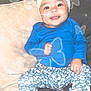 baby, blue_clothing, bow, butterfly_effects, child, couch, cute, floral_pants, footwear, glow, happy, headband, indoor, nike, person, portrait, sitting, smiling, sneakers, toddler