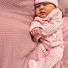 Devahni is registered to the contest to win money with this photo: baby, sleeping, pink, striped_clothing, hat, pajamas, cushion, texture, infant, peaceful, resting, cozy, soft, cute, child, portrait, indoor, closeup, newborn, relaxation