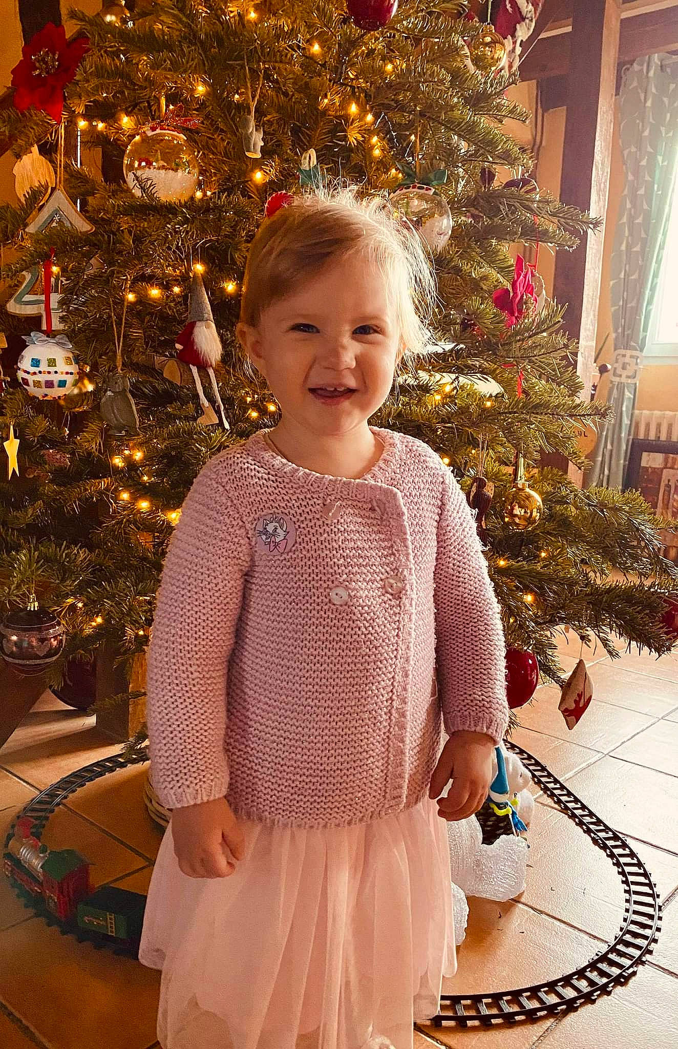 Lia participe au concours pour gagner de l'argent avec cette photo : baby_toddler_clothing, christmas, christmas_decoration, christmas_ornament, christmas_tree, evergreen, fun, happy, holiday, holiday_ornament, human_body, joy, lighting, ornament, person, plant, sleeve, smile, standing, toddler