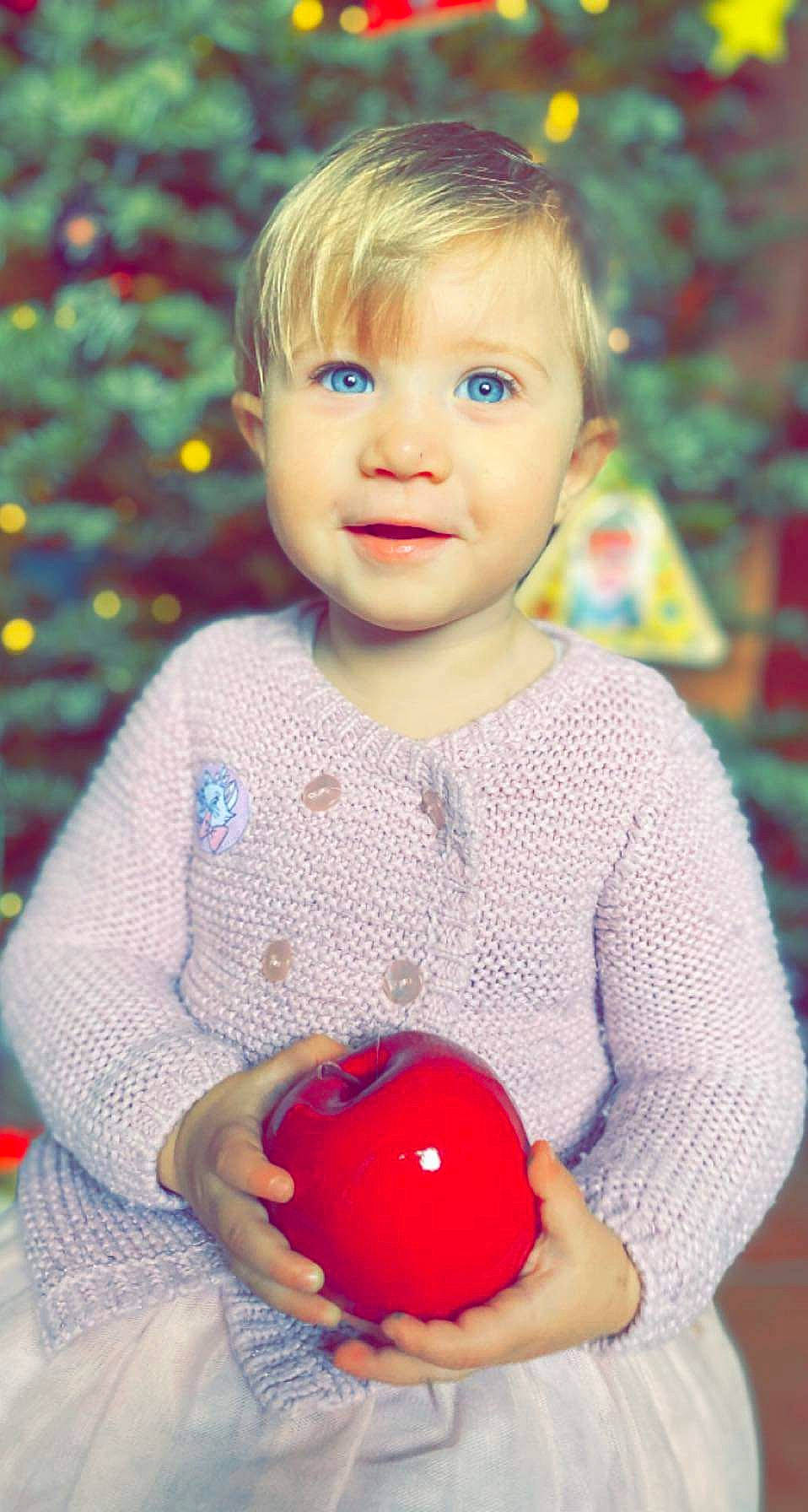 Lia participe au concours pour gagner de l'argent avec cette photo : baby_toddler_clothing, cheek, child, christmas_ornament, event, face, facial_expression, fun, grass, happy, head, organ, people_in_nature, person, plant, red, sleeve, smile, standing, toddler