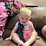 Everitt is registered to the contest to win money with this photo: toddler, child, smiling, indoor, couch, blanket, romper, stars, stripes, american_flag_theme, barefoot, happy, sitting, furniture, person, face, blond_hair, skin, hand, foot