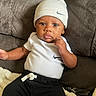 Toussaint joined the competition — help win amazing prizes! baby, infant, child, portrait, sitting, couch, blanket, beanie, hat, clothing, nike, black_pants, white_shirt, brown_couch, cozy, indoors, face, serious_expression, hand, photography