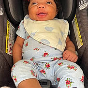 Royalyn is registered to the contest to win money with this photo: baby, infant, car_seat, smiling, headband, bib, floral_outfit, clothing, happy, child, seatbelt, safety, portrait, closeup, indoor, person, cute, young_child, red_headband, small_child