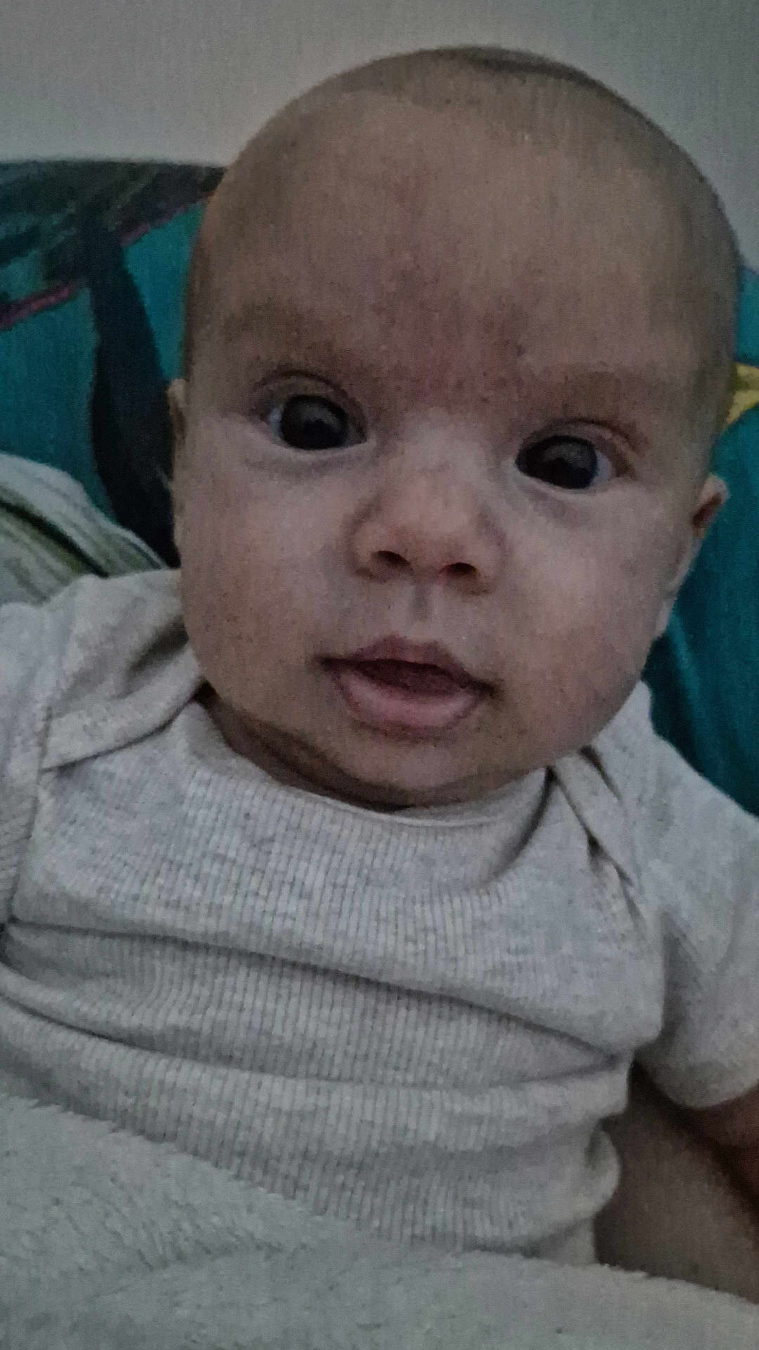 Albin participe au concours pour gagner de l'argent avec cette photo : baby, infant, face, close_up, onesie, blanket, curious, wide_eyes, mouth_open, head, skin, person, portrait, child, indoors, soft_texture, fabric, colorful_background, resting, young