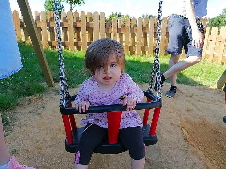 Norah participe au concours pour gagner de l'argent avec cette photo : baby_toddler_clothing, child, city, event, fun, grass, happy, human_settlement, leisure, outdoor_play_equipment, person, plant, play, playground, recreation, shorts, sitting, sky, swing, toddler