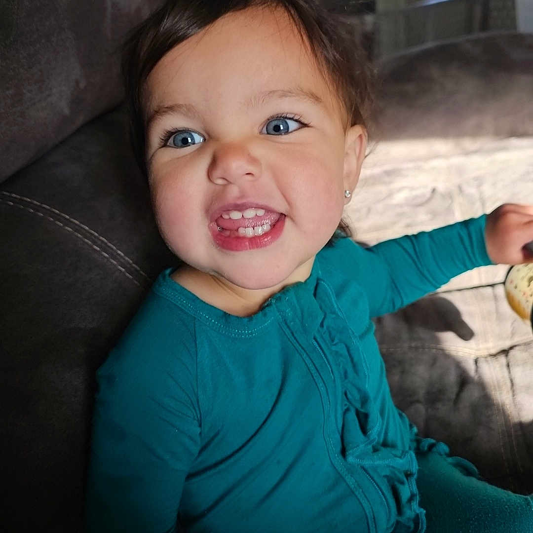 Evelyn joined the competition — help win amazing prizes! baby, bodypart, clothing, coat, couch, cushion, face, finger, furniture, happy, head, homedecor, jacket, mouth, pants, person, photography, portrait, smile, teeth