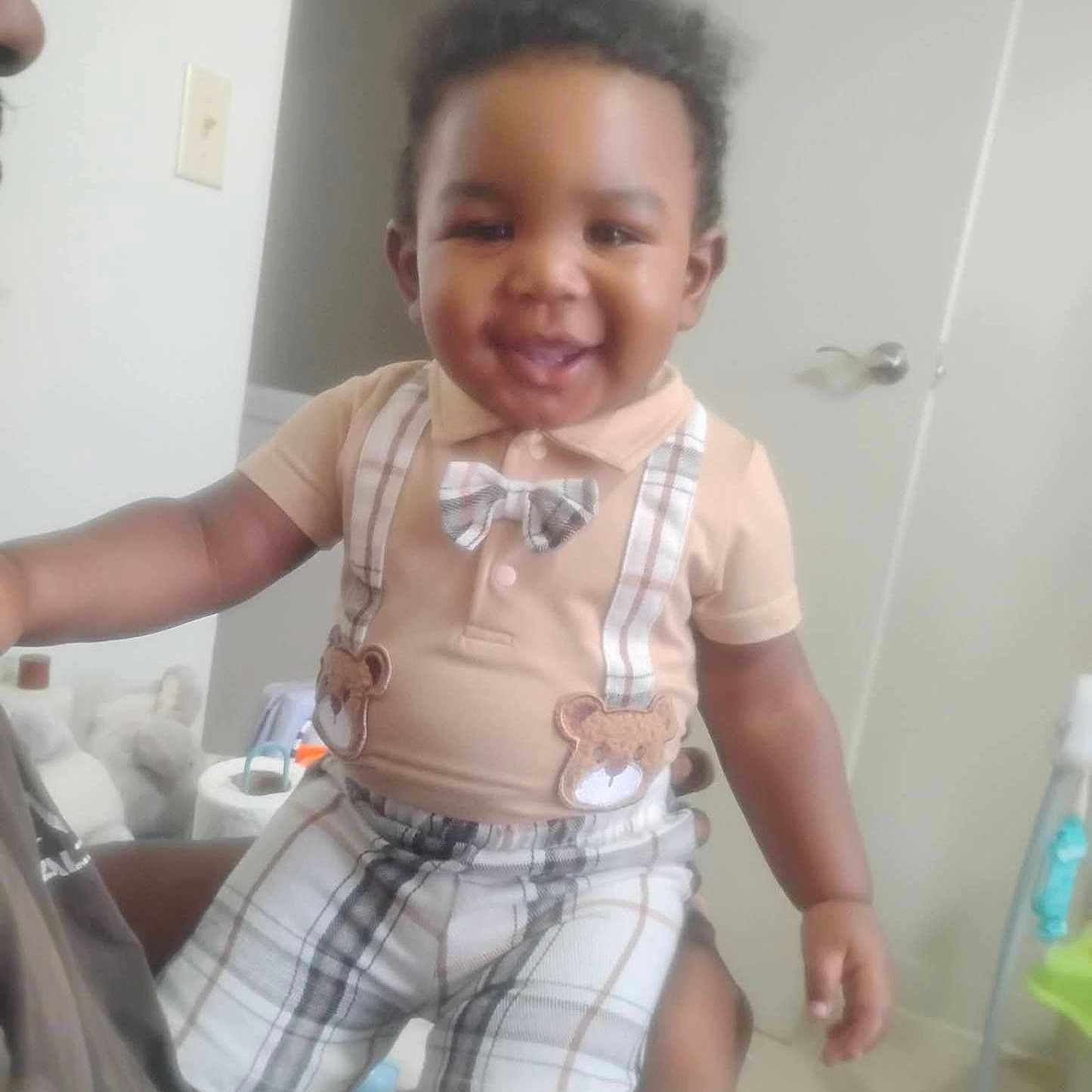 Bobby joined the competition — help win amazing prizes! toddler, child, smiling, indoor, plaid, bow_tie, suspenders, person, cute, happy, clothing, baby, short_sleeve, holding, adult, door, room, furniture, floor, light_switch