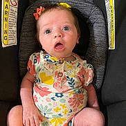 Sage joined the competition — help win amazing prizes! baby, infant, car_seat, onesie, floral_pattern, hair_bow, wide_eyes, surprised_expression, sitting, child, warning_label, safety, clothing, cute, indoors, person, skin, head, face, seat