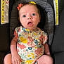 baby, infant, car_seat, onesie, floral_pattern, hair_bow, wide_eyes, surprised_expression, sitting, child, warning_label, safety, clothing, cute, indoors, person, skin, head, face, seat