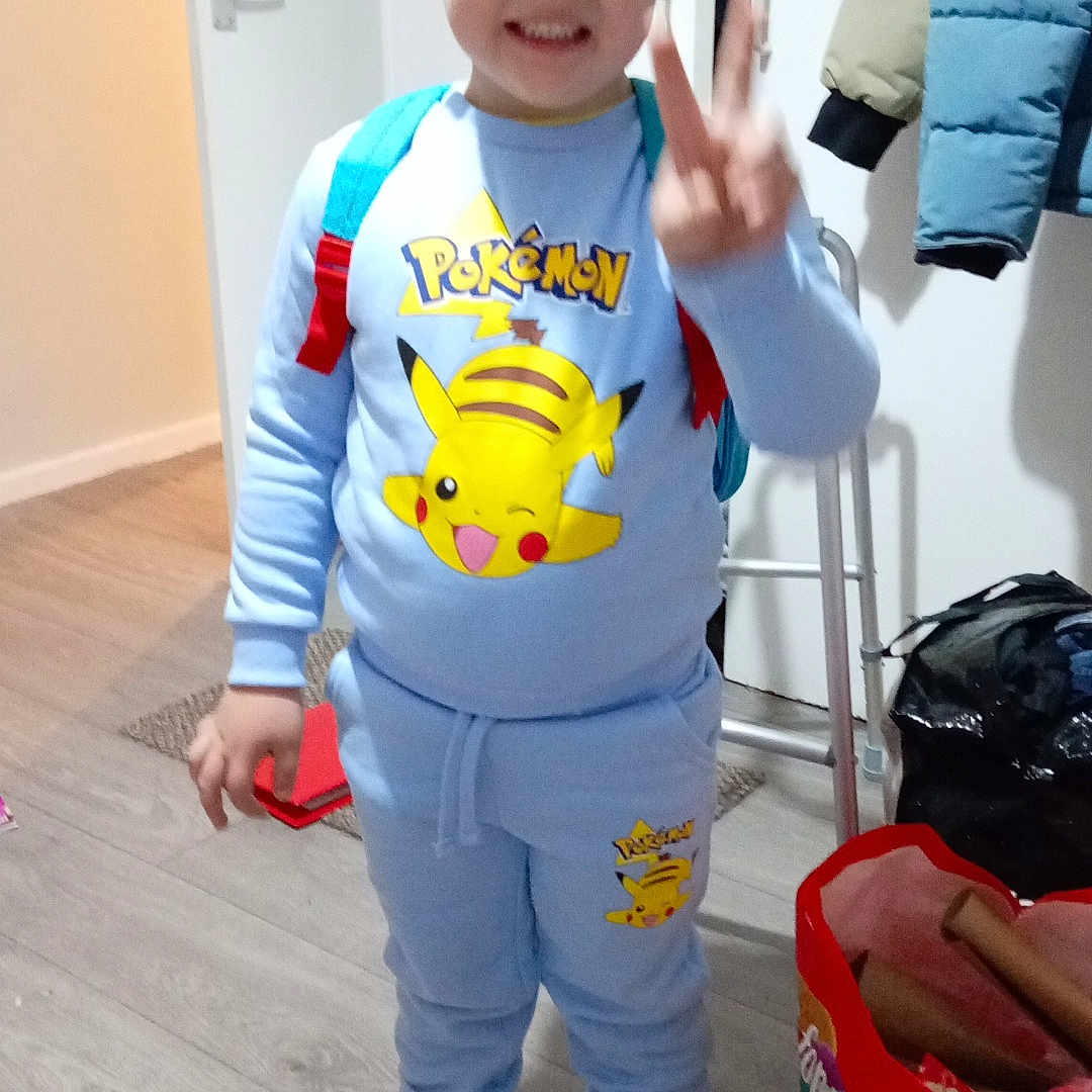 Grayson Francis is registered to the contest to win money with this photo: backpack, bag, boy, casual, child, clothing, coat, door, floor, happy, indoor, peace_sign, person, pokemon, room, shoes, smiling, standing, toy, young
