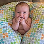 baby, infant, smiling, hands, face, pillow, pattern, colorful, couch, seated, cute, happy, skin, closeup, indoor, child, young, comfort, expression, portrait