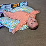 baby, infant, child, carpet, pillow, floral_pattern, orange_clothing, blanket, toy_ball, floor, cute, smiling, lying_down, indoors, face, head, hands, feet, person, happy