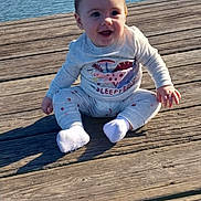 Jaelynn is registered to the contest to win money with this photo: baby, child, dinosaur, socks, outdoor, dock, water, lake, sky, smiling, happy, wood, clothing, sitting, nature, sunlight, cute, portrait, infant, casual