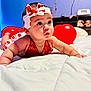 baby, infant, headband, bow, red_balloon, bed, blanket, cute, portrait, big_eyes, chubby_cheeks, earrings, red_dress, nursery, toy, shelf, wall, colorful, playtime, expression