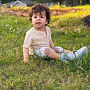 Ravaymaan joined the competition — help win amazing prizes! child, toddler, grass, outdoor, curly_hair, sitting, beige_shirt, patterned_shorts, sneakers, greenery, sunlight, garden, portrait, young_child, nature, daylight, casual_clothing, expression, background, house