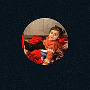 Iknoor is registered to the contest to win money with this photo: black_leggings, blanket, child, container, cozy, cute, floor, home, indoors, orange, person, pigtails, playful, portrait, red, sitting, smiling, sweater, toddler, video_call