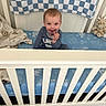 Mason joined the competition — help win amazing prizes! baby, child, infant, crib, nursery, sitting, smiling, face, portrait, pacifier, teething_ring, blue_bedding, white_crib, stuffed_animal, teddy_bear, blanket, mattress, indoor, home, cozy