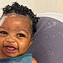 baby, child, curly_hair, soap, bath, smile, happy, face, water_bubbles, skin, person, cute, indoors, head, blue_clothing, infant, closeup, cheerful, washing, sitting