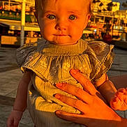 Lillie joined the competition — help win amazing prizes! baby, child, infant, person, face, hand, sunlight, outdoor, clothing, ruffle, skin, portrait, cute, holding, expression, legs, urban, background, warm_light, daylight