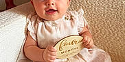 Lillie joined the competition — help win amazing prizes! baby, child, infant, four_months, blue_eyes, bow, dress, sitting, plaque, wooden_sign, cozy_chair, textured_fabric, cute, smiling, portrait, indoor, soft_lighting, pastel_colors, happy, young