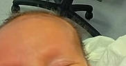 Colin is registered to the contest to win money with this photo: baby, blanket, chair, closeup, face, feeding_tube, floor, healthcare, hospital, indoors, medical_equipment, newborn, older_adult, person, resting, screen, sleeping, smiling, technology, video_call