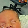baby, blanket, chair, closeup, face, feeding_tube, floor, healthcare, hospital, indoors, medical_equipment, newborn, older_adult, person, resting, screen, sleeping, smiling, technology, video_call